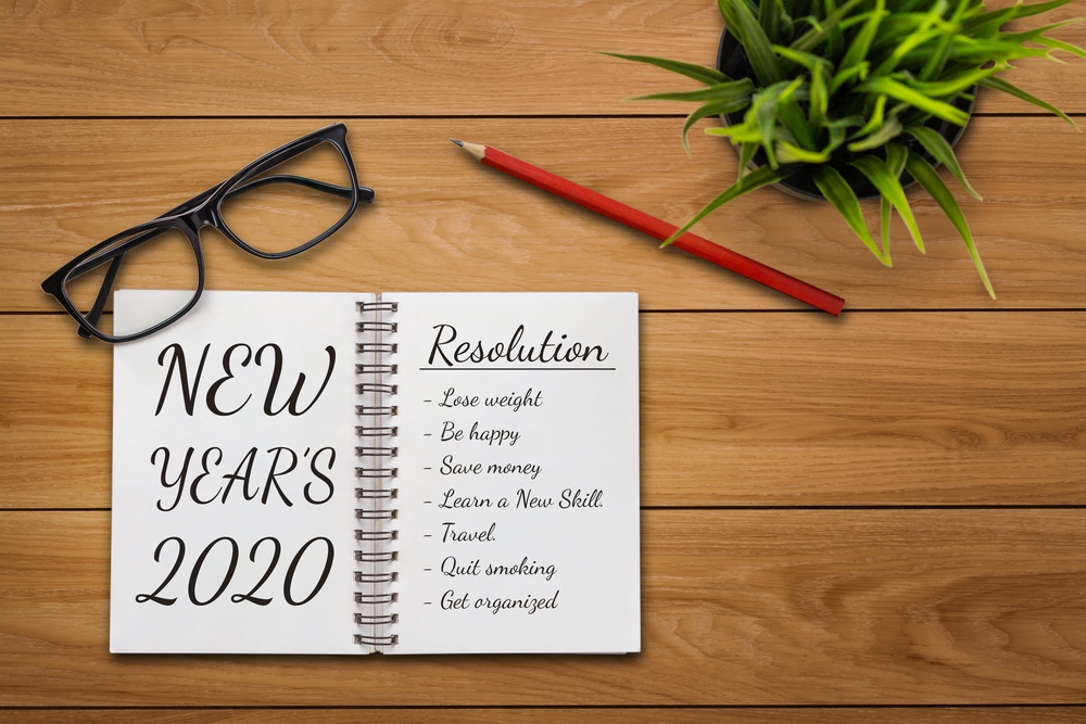 New Year Resolution Goal List 2020 - Business office desk with notebook written in handwriting about plan listing of new year goals and resolutions setting. Change and determination concept.