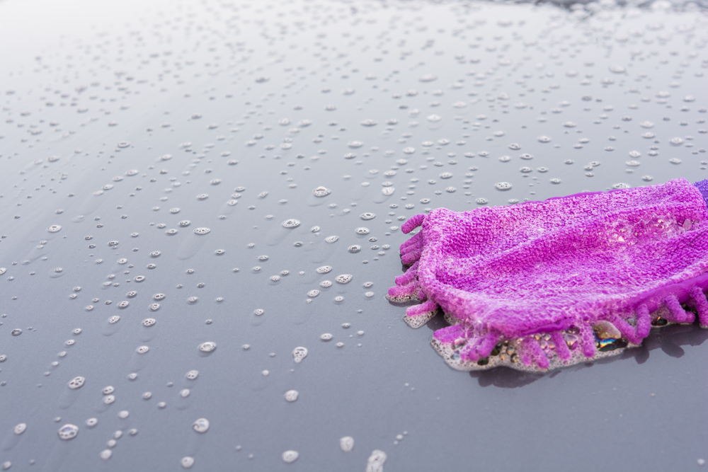 Closeup cleaning his car using gloves car wash gray color