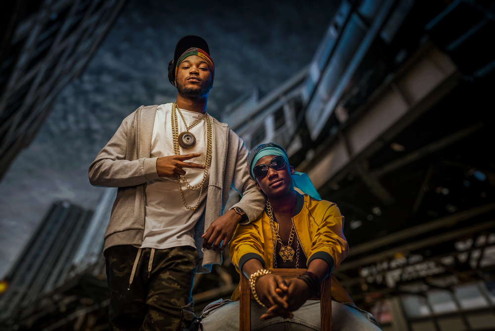 Two black rappers poses on night city street, skyscrapers on background. Rap performers against cityscape, underground music concert, urban style