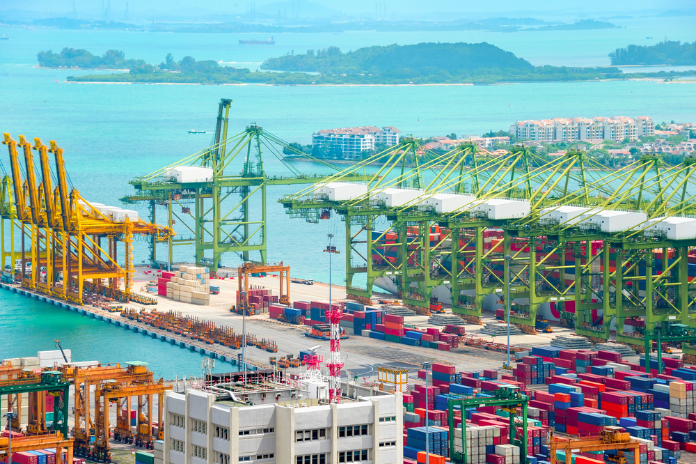Singapore commercial port aerial view, freight cranes and containers at pier, islands and ships in background
