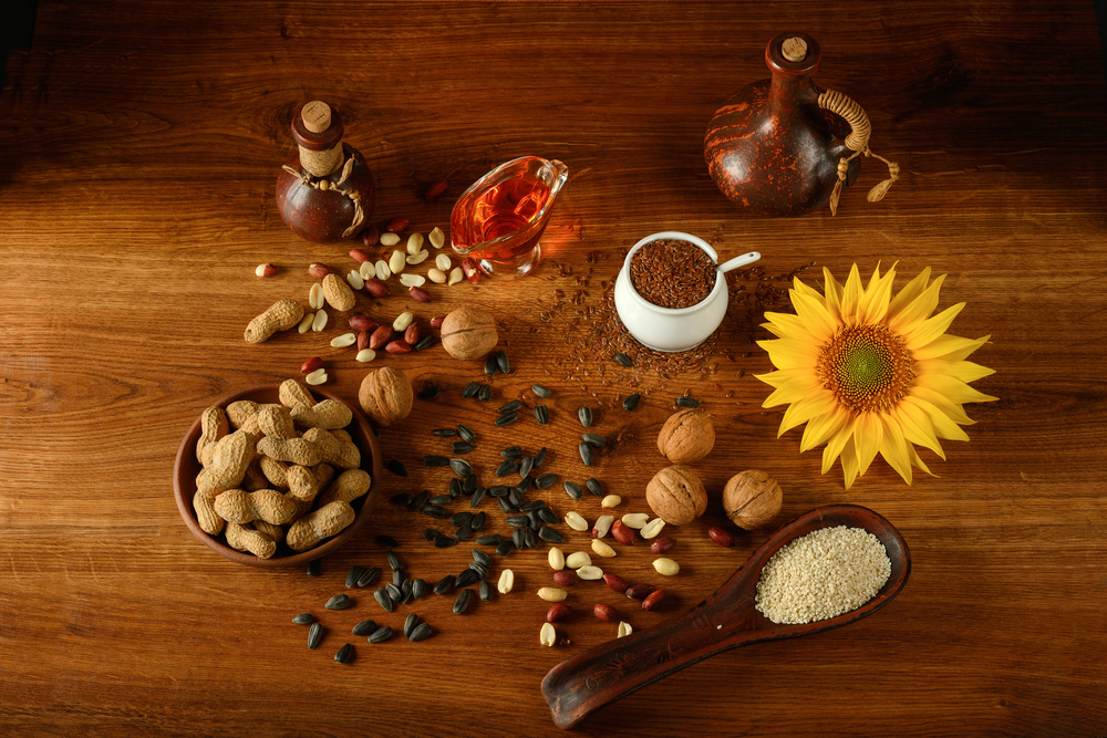 Vegetable oil in bottles, healthy seeds and nuts on old wooden floor