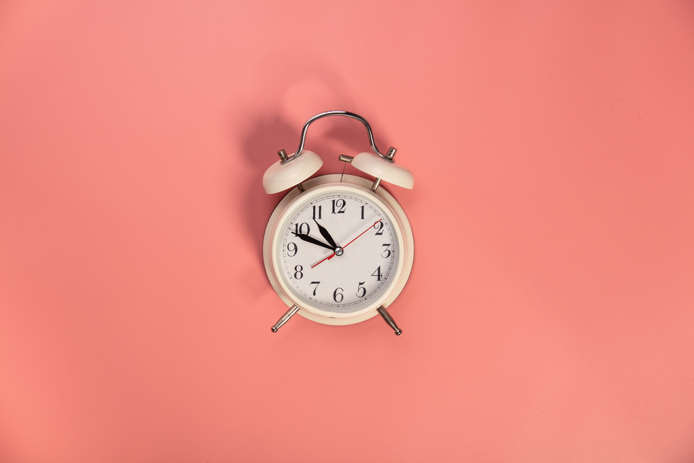White alarm clock on pink background . White alarm clock on pink background - flat lay