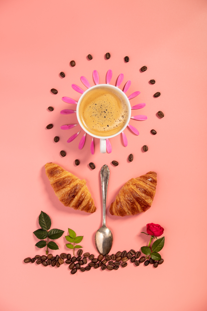 Creative layout made of alarm clock, croissants, coffee beans and flowers on pink background, flat lay