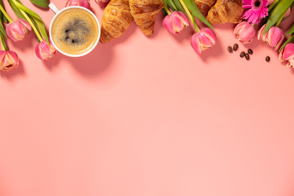 Morning coffee, croissants and a beautiful flowers on pink background with space for text. Cozy breakfast. Flat lay composition for bloggers, magazines, web designers, social media and artists.