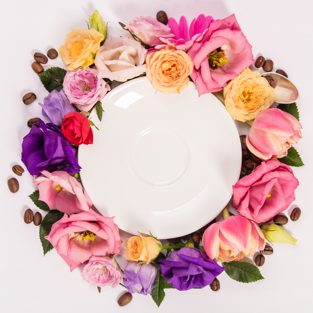 Still life composition with plate and various colorful pastel garden flowers, flat lay