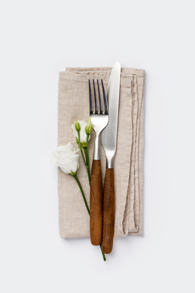 Fork, knife and flowers on white background, flat lay