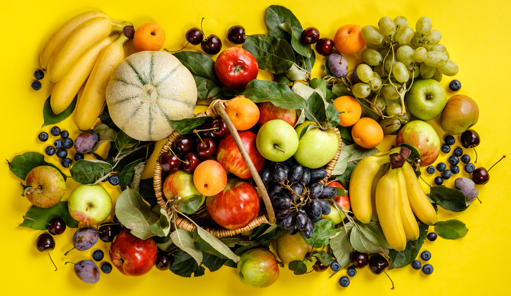 Flat-lay of fresh fruits and berries on yellow background. Top view. Vegetarian, clean eating, raw food concept