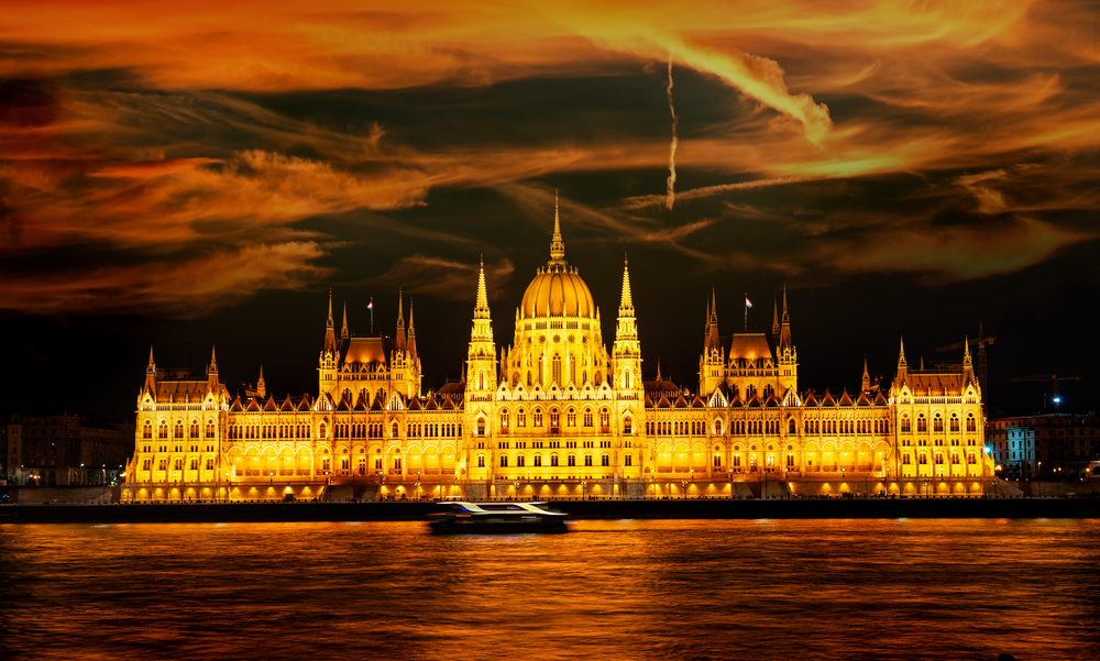 Facade of illuminated Budapest Parliament under cloudy sky, Hungary