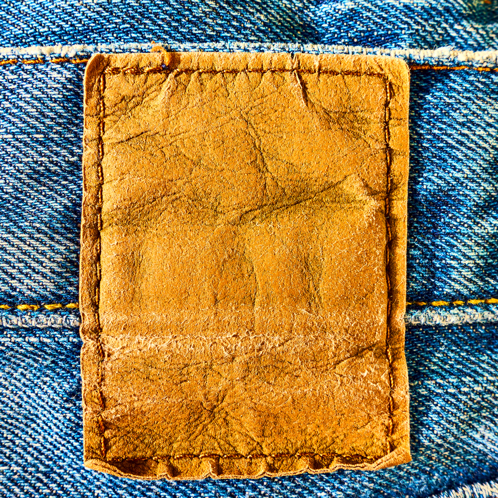 Blank leather label sewed on a blue jeans close-up