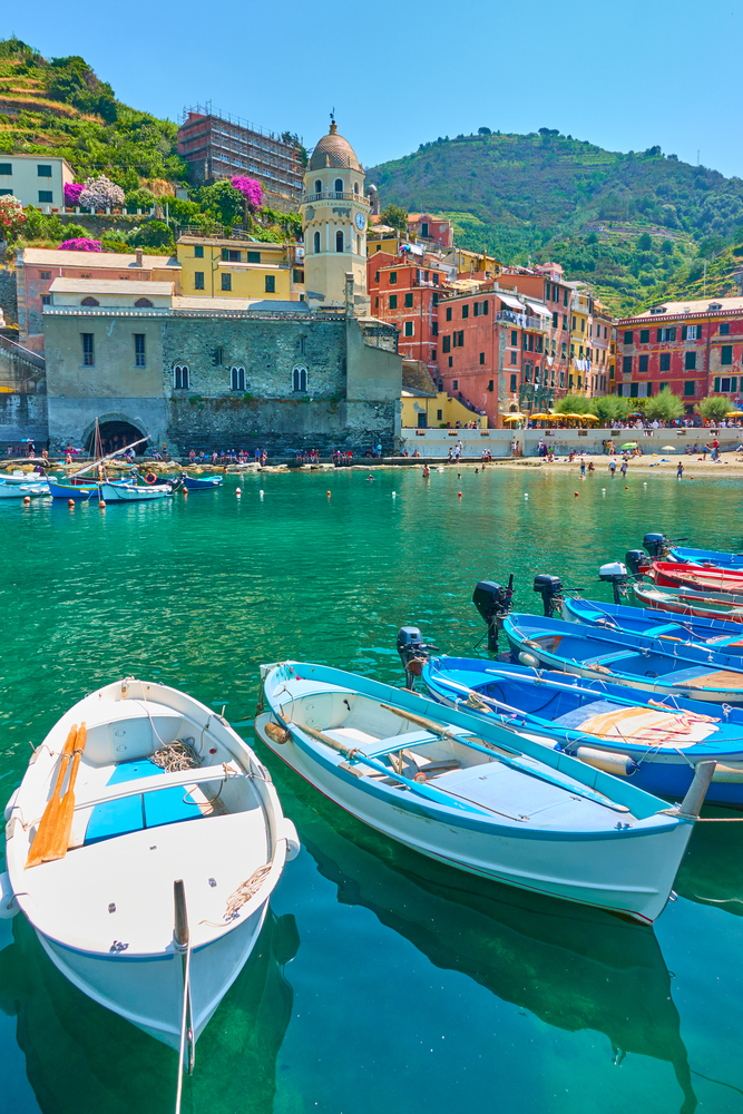 Boats at harbour and waterfront with buildings by the sea in Vernazza town on sunny summer day, Cinque Terre, Italy