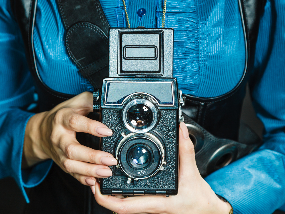 Photography and retro style. Young vintage attractive girl holds old aged camera. Steampunk photographer taking photo.. Steampunk with old retro camera.