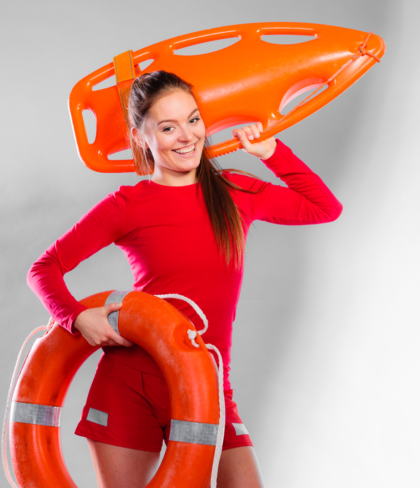 Accident prevention and water rescue. Young woman female smiling lifeguard on duty holding lifesaver equipment on gray