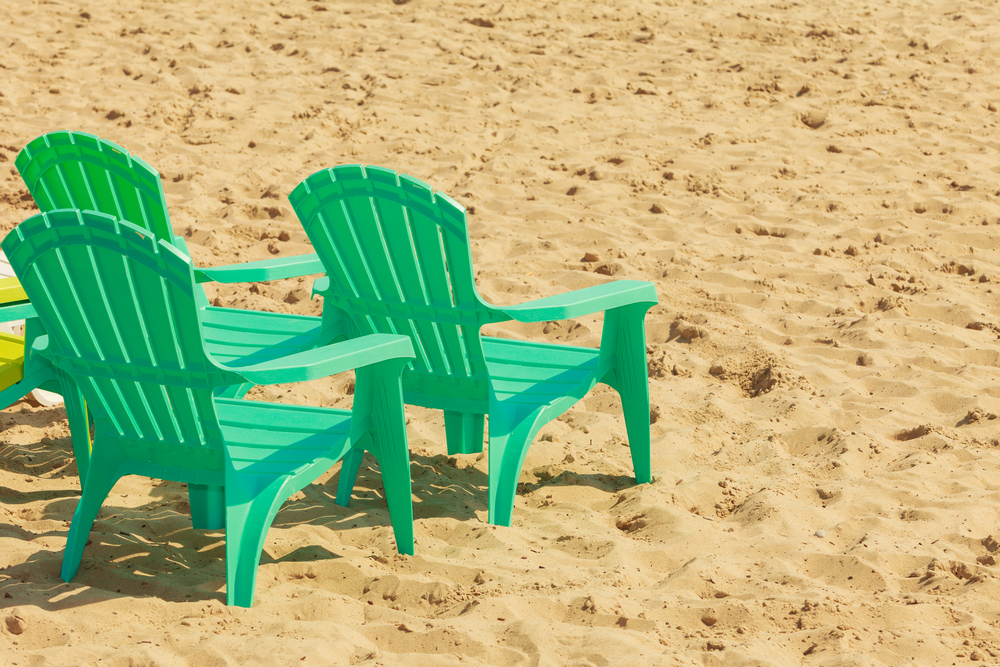Rest and relax in summer. Three green plastic chairs on sand. Relaxation place on sunny beach.. Green plastic chairs on sand.