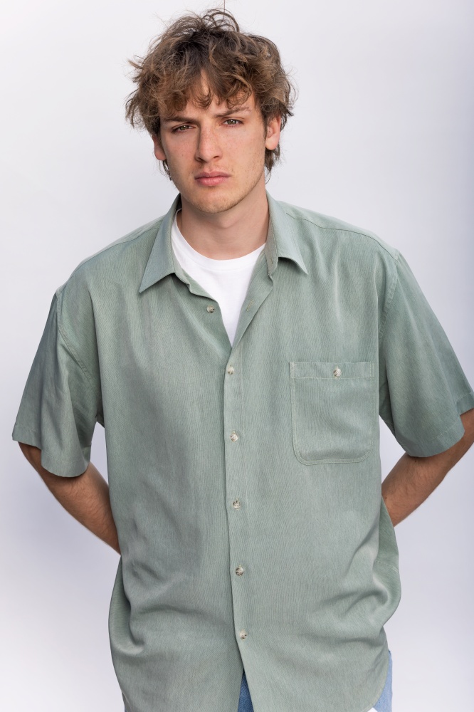 White background studio portrait of a handsome cool young man boy teenager teen young adult male wearing a white t-shirt and green shirt