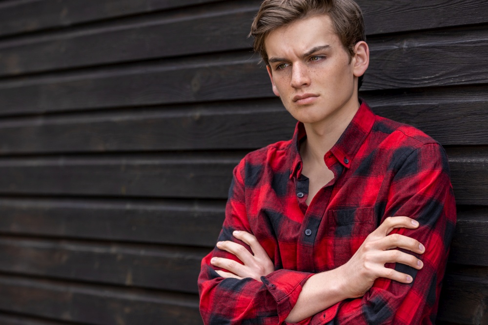 Handsome sad depressed or thoughtful teenager teen male boy teen young adult wearing a red and black shirt