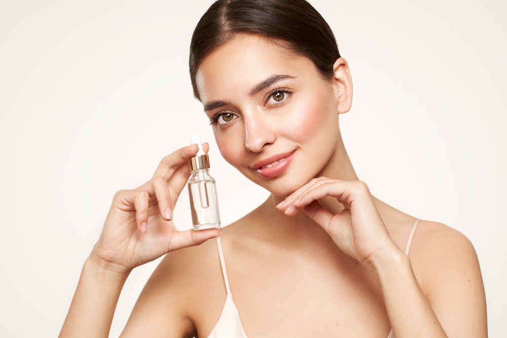 Beautiful elegant woman holding a cosmetic jar of oil serum or hyaluronic acid in her hand. Perfect facial skin