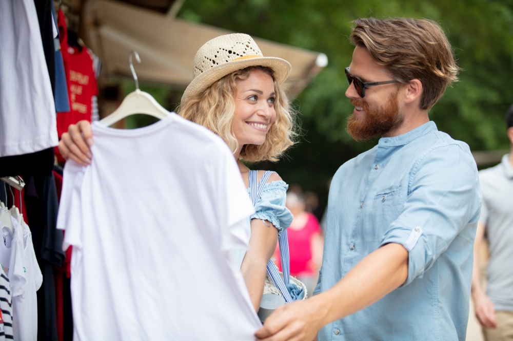 happy couple buying t-shirt outdoors