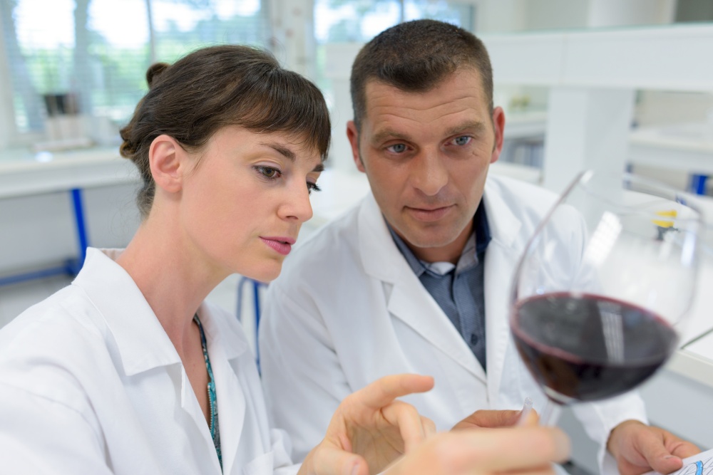 man and woman experts in white coats checking wine quality