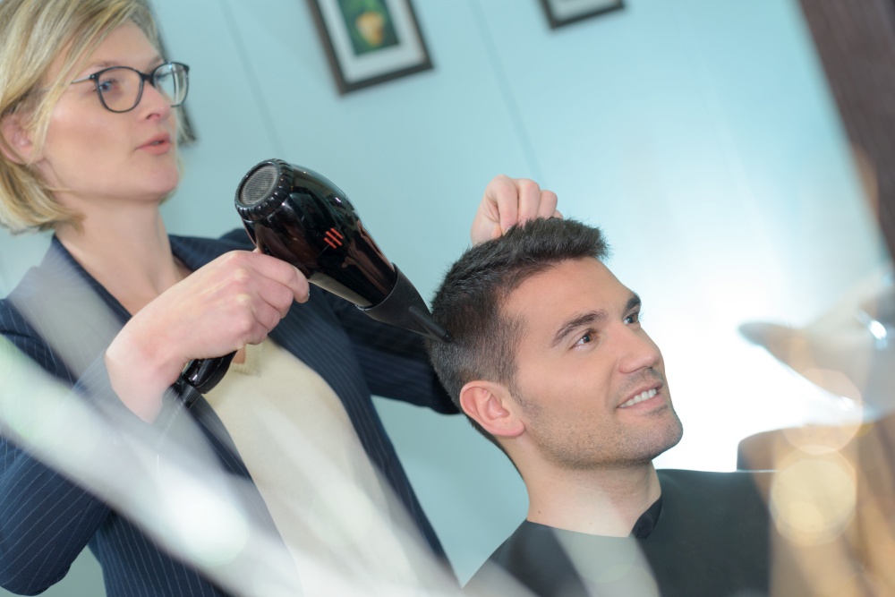 female hairdresser drying her male customers hair