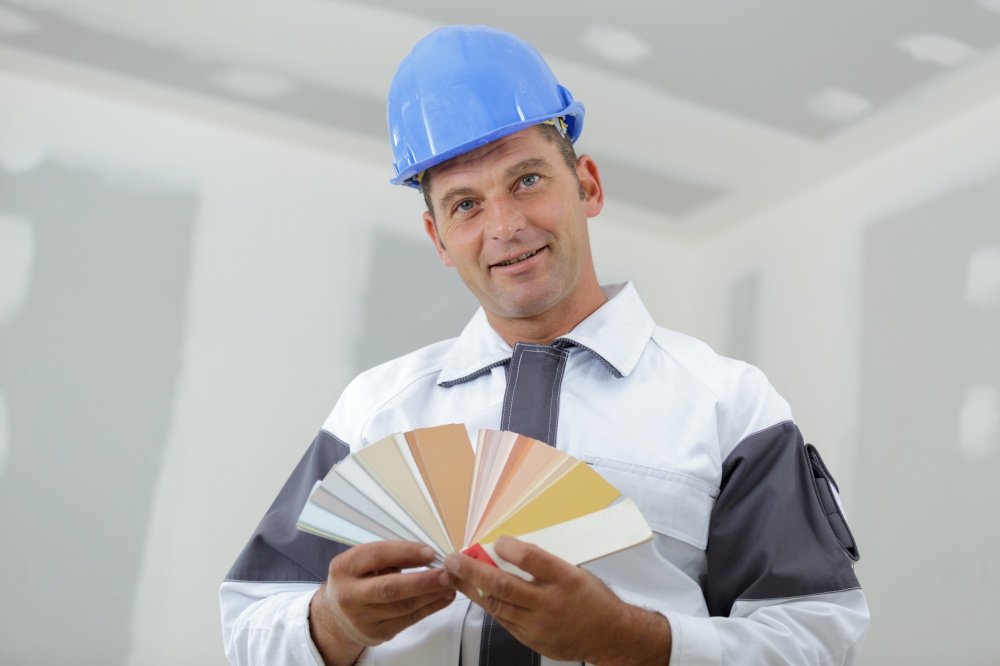 painter in blue workwear holding color swatches