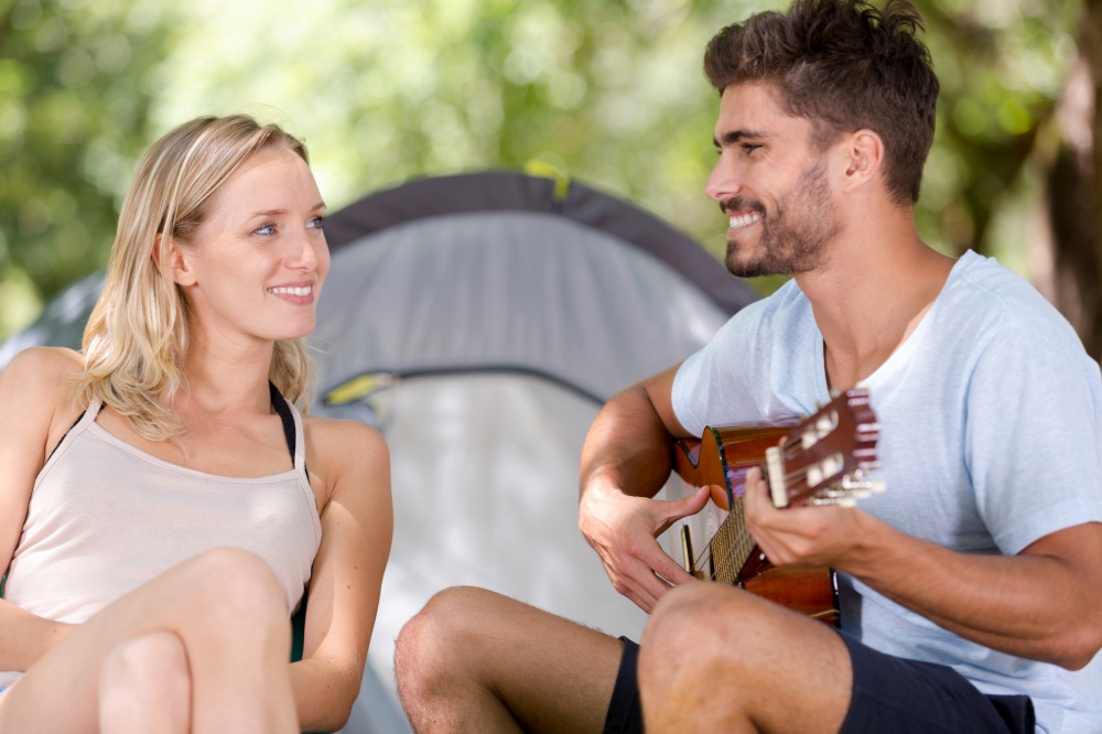 young man playing his guitar with girlfriend