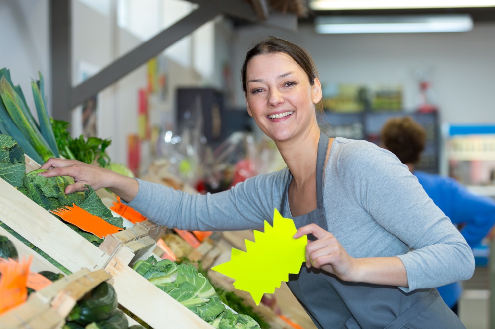 happy woman wearing apron and selling fruits in shop