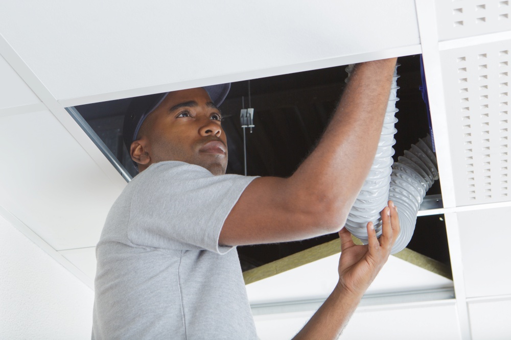 Man fiiting plastic hose into roof space