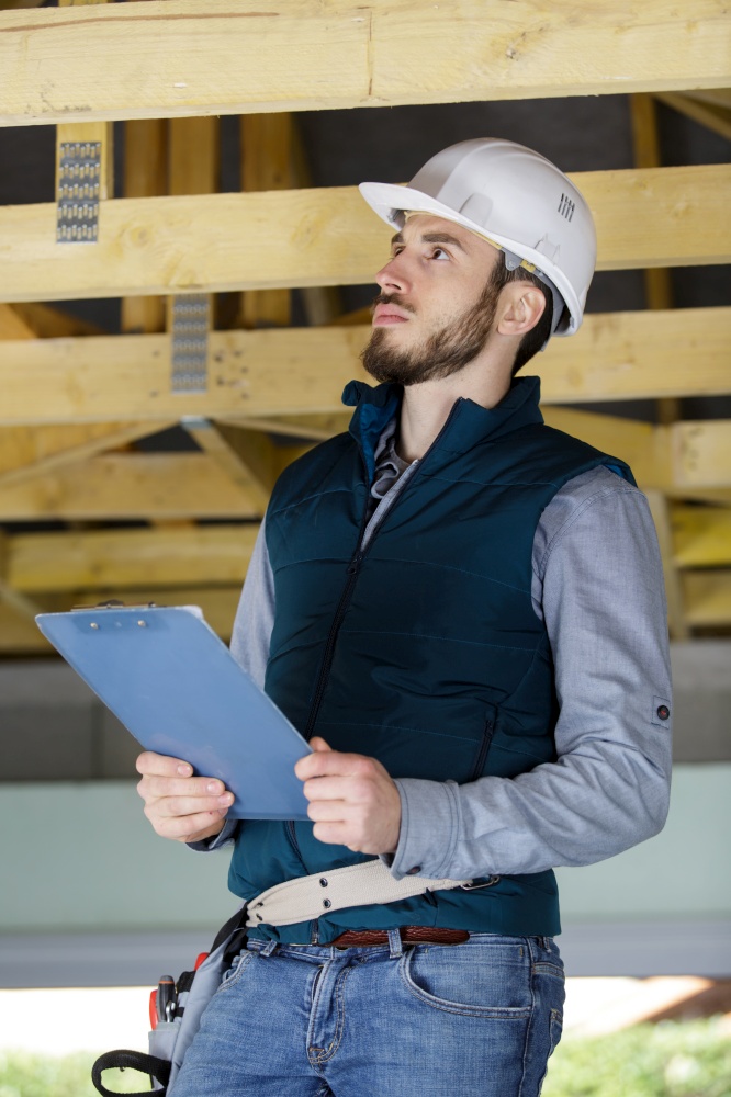 young constructor engineer man marking a wood structure