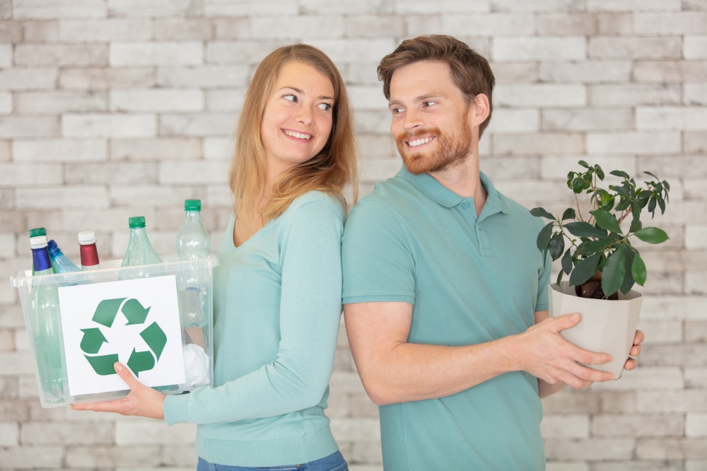 ecological couple hold a plastic container and a small tree