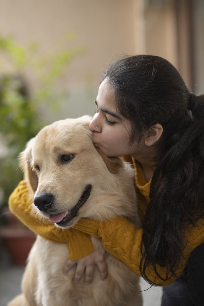 A YOUNG GIRL HAPPILY KISSING PET DOG