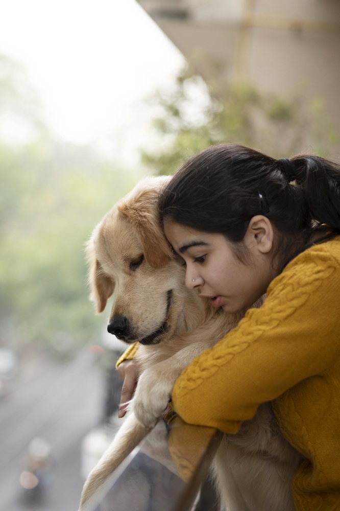A YOUNG GIRL AND PET DOG LEANING OVER RAILING AND LOOKING DOWN