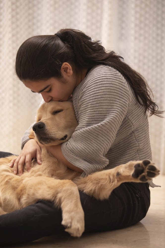A TEENAGER HUGGING AND KISSING PET DOG WHILE AT HOME