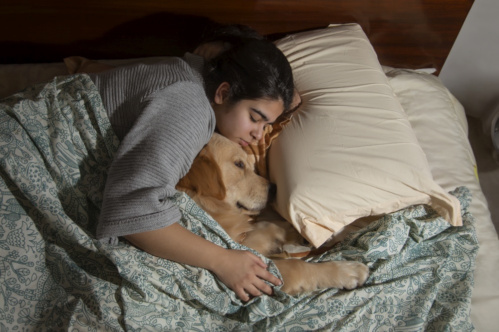 A YOUNG GIRL CUDDLING PET DOG AND SLEEPING