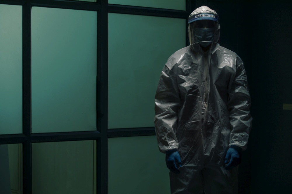 Doctor standing in a protective suit standing in the dark