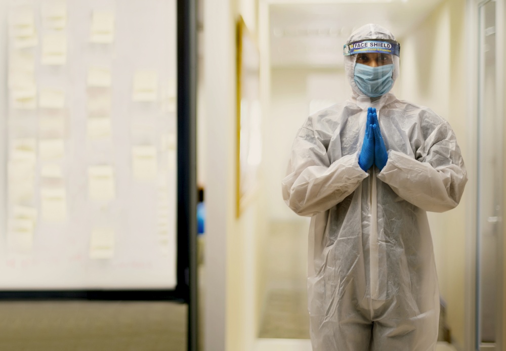 Doctor in a protective suit standing with his hands joined