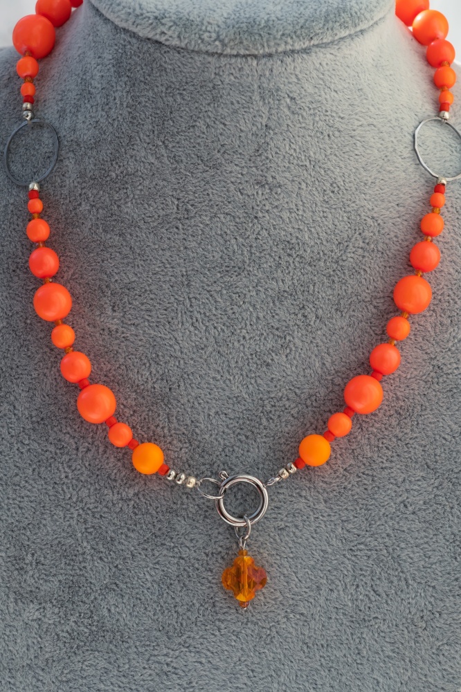 author beautiful  fashionable  necklace with neo orange pearls  demonstrated at model. fashion and jewelry concept