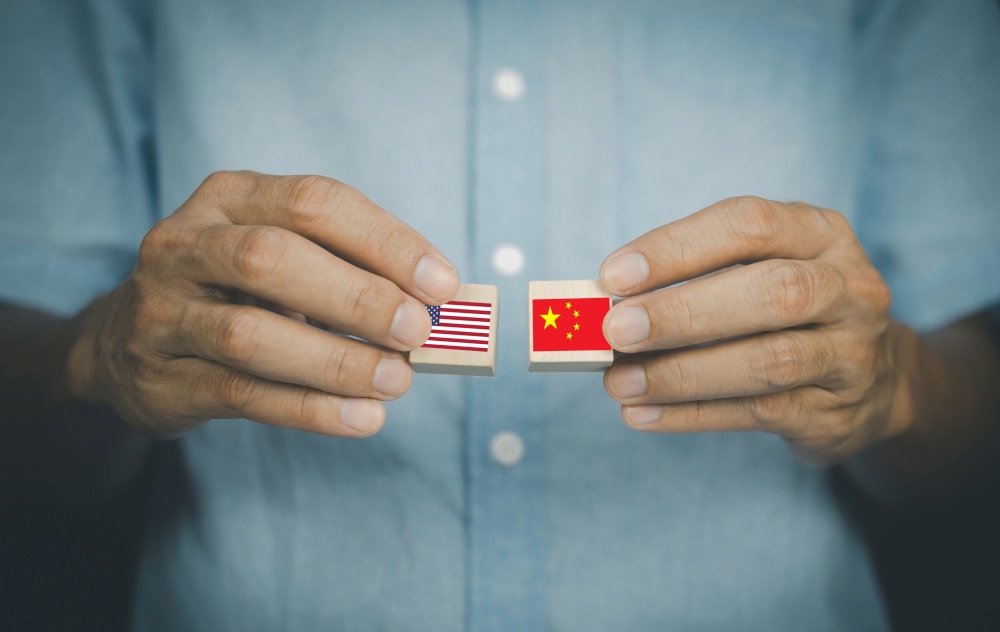 hand holding wood block concept business import export United States of America and China,US and China flag trading punches for the concept: Trade War.