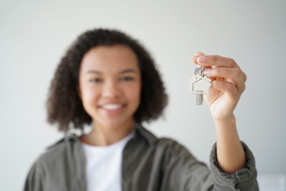Happy biracial teen girl homeowner tenant shows keys to new home, close-up. Smiling young mixed race lady holding key to apartment, focus on hand. Mortgage, housing rental service advertisement.. Happy biracial teen girl homeowner tenant shows keys to new home, close-up. Mortgage, rental housing