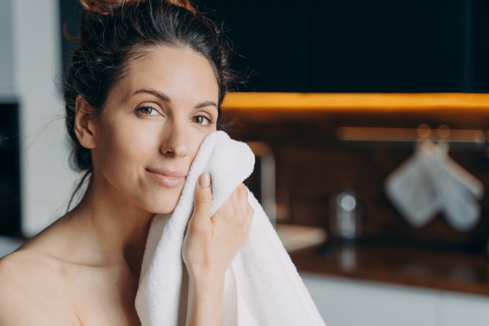 Pretty young latina woman wipe rub face with towel after shower, female do morning beauty procedures enjoying healthy smooth skin at home looking at camera. Hygiene, skincare concept.. Pretty girl wipe face with towel after shower, enjoy healthy smooth skin at home. Hygiene, skincare
