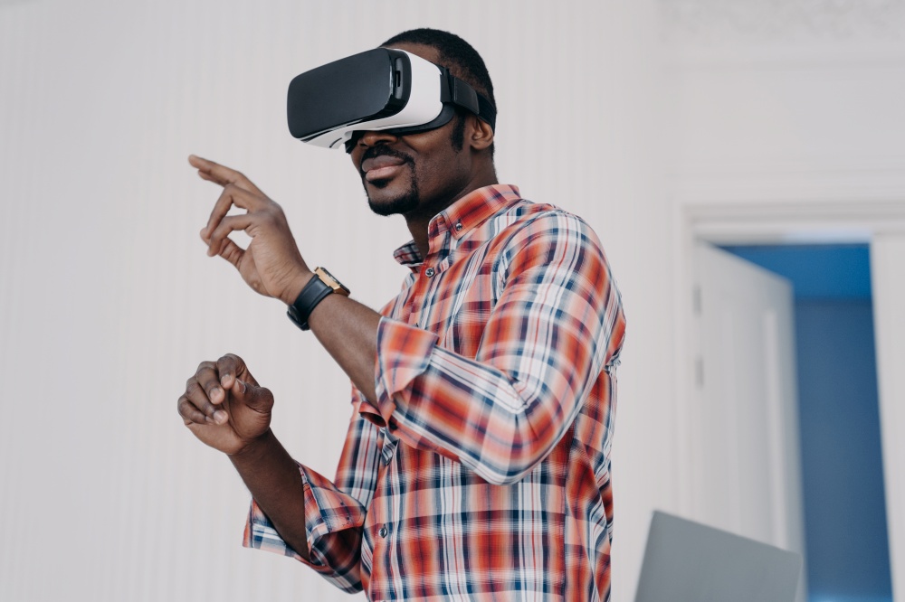 African american man wearing VR glasses touching virtual objects by fingers, interacting with cyberspace. Modern black guy in virtual reality goggles playing online video game. High tech concept.. African american man in vr glasses, interact with virtual augmented reality, play online video game