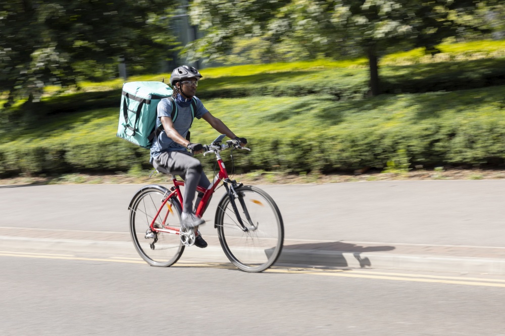 Courier On Bike Delivering Takeaway Food In City