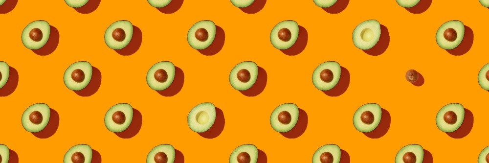 Banner. Avocado on orange background pattern top view flat lay. Summer color. Minimal concept