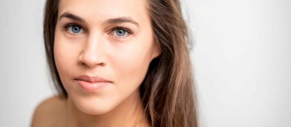 Face portrait of young caucasian woman with natural make up and eyelash extensions looking at camera on white background. Face portrait of young caucasian woman