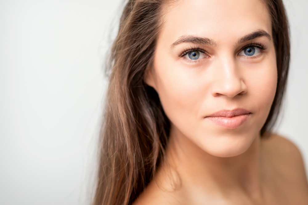 Face portrait of young caucasian woman with natural make up and eyelash extensions looking at camera on white background. Face portrait of young caucasian woman