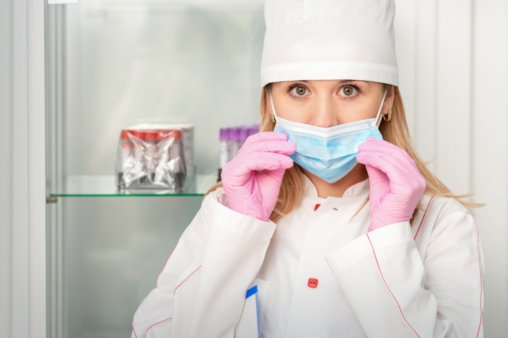 Female nurse or doctor wears protective gloves putting on medical face mask in the lab. Nurse putting on medical face mask