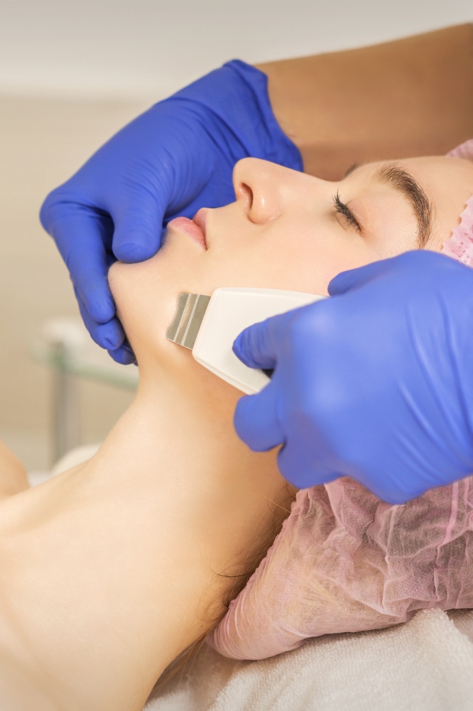 Beautiful young woman receiving ultrasonic cavitation facial cleansing in beauty spa salon. Woman receiving ultrasonic facial cleansing