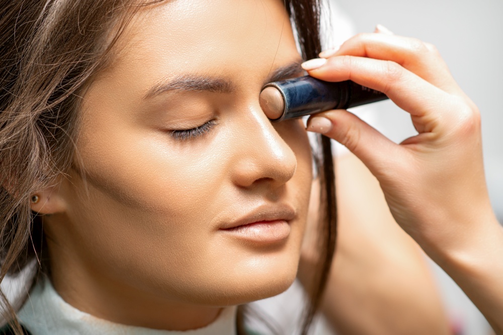 Make up artist contouring the face of a young woman with cream blush close up. Make up artist contouring the face of a young woman with cream blush close up.