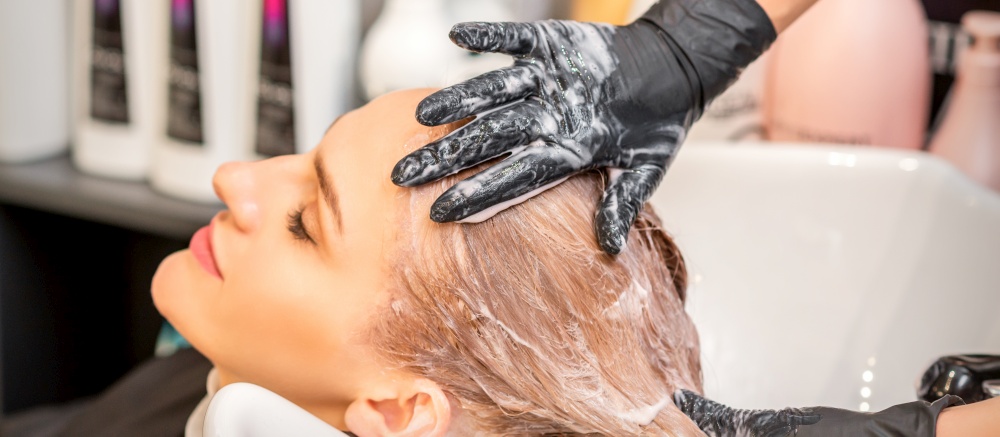 Young caucasian blonde woman having hair washed in the sink at a beauty salon. Young caucasian blonde woman having hair washed in the sink at a beauty salon.