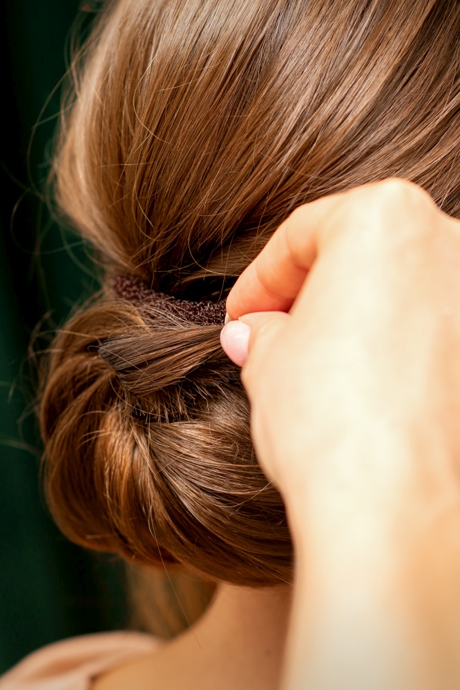 Hands of hairdresser making french twist hairstyle of an unrecognizable young brunette woman in a beauty salon, back view, close up. Hands of hairdresser making french twist hairstyle of an unrecognizable young brunette woman in a beauty salon, back view, close up.