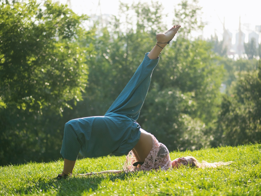 Young yogi woman stretching legs in park. Yoga time. Green grass, park, summer morning. Relaxing and meditating, Health concept. High quality photo. Young yogi woman stretching legs in park. Yoga time. Green grass, park, summer morning. Relaxing and meditating, Health concept.